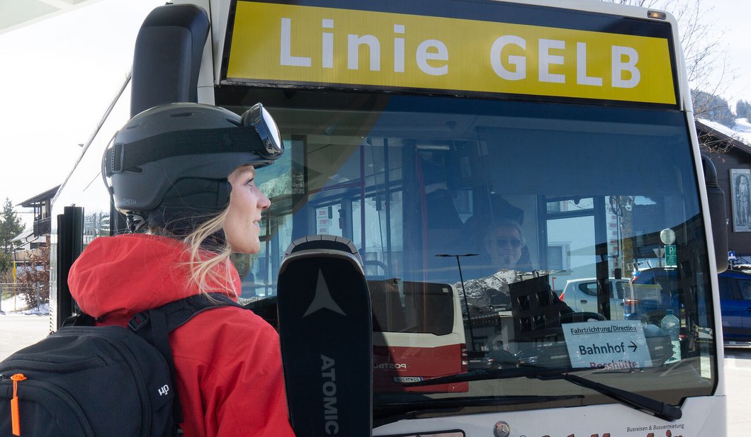 Skifahrerin mit Ski beim Einsteigen in den Skibus