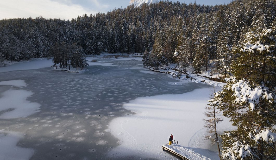 Winterwandern Paar Möserer See - Drohnenaufnahme - Paar steht am Steg Blick Richtung Hohe Munde 