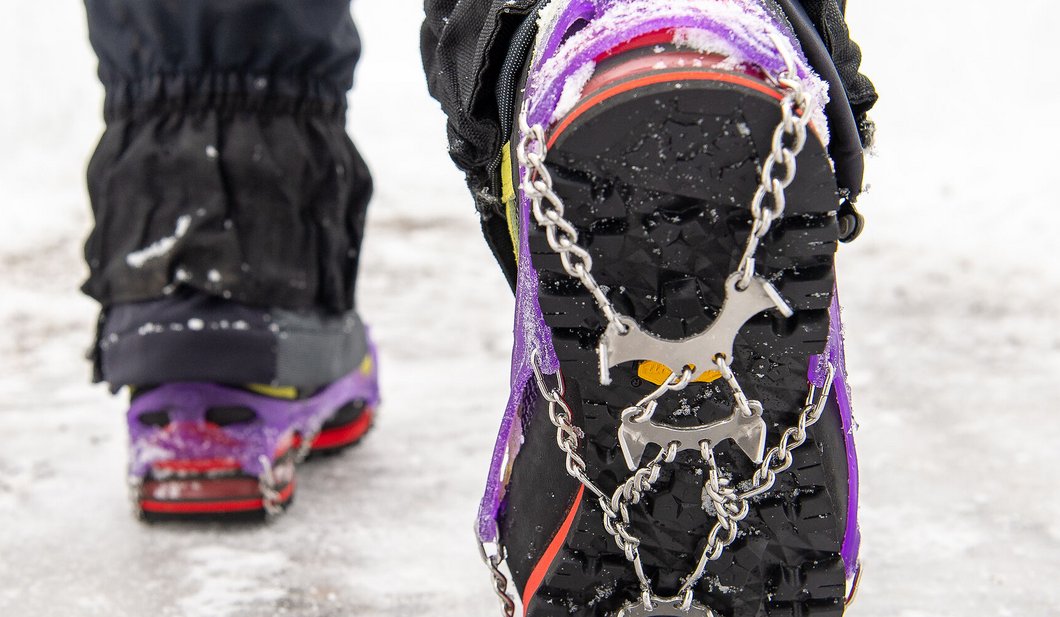 Winterschuh mit Grödel auf verschneitem Weg