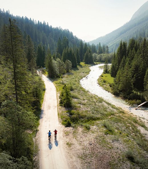 E-Biken im Gaistal im Sommer Drohnenaufnahme zwei Bikerinnen fahren entlang der Ache