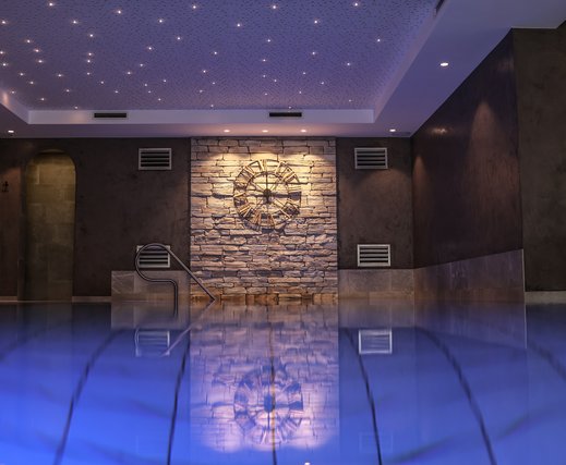 Blauer Indoorpool mit Sternenhimmel und antiker Uhr an der Wand